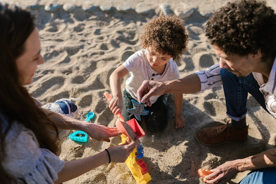 Parents and child playing with sand toys at the beach enjoying quality time outdoors