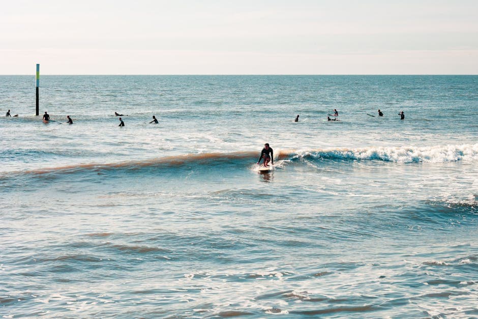 Boscombe beach and pier with the surf reef visible beneath the waves and surfers in the water