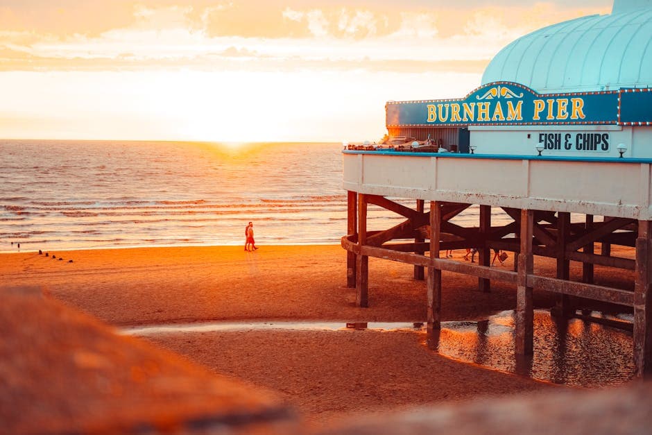 Warm golden light on a seaside pier at sunset with people enjoying the coastal view from the promenade