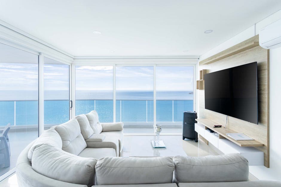 Bright and spacious holiday apartment living room with ocean views and modern white furnishings