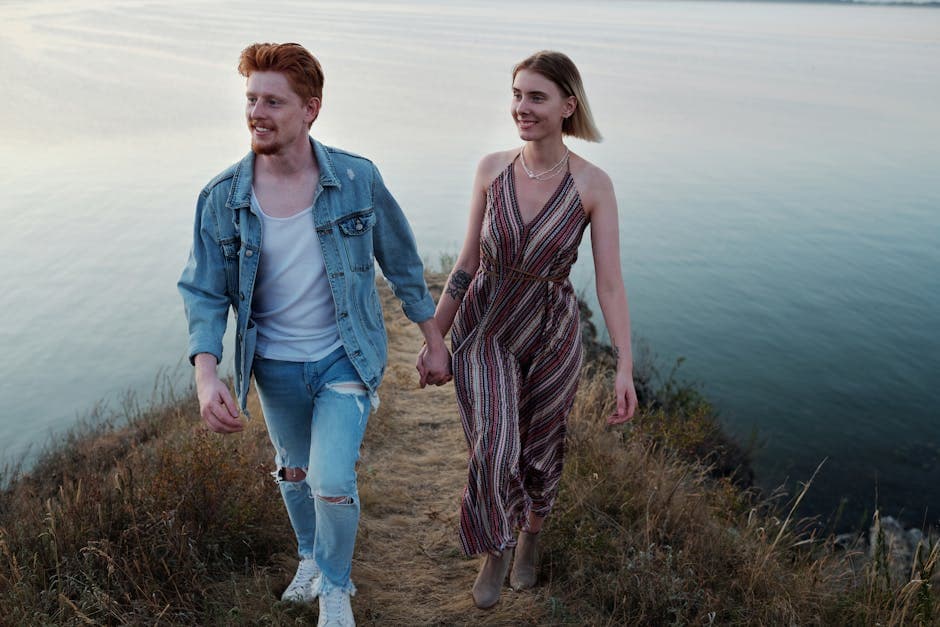 A young couple walking hand in hand along a scenic cliffside path overlooking the sea