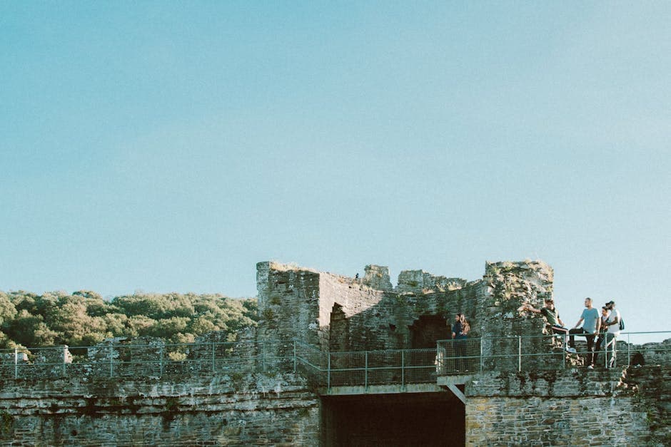 Ancient stone castle ruins on a hilltop, with visitors exploring the historic walls and towers
