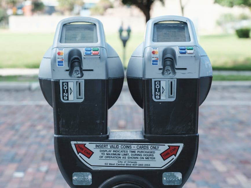 Two parking payment meters on a brick-paved street showing coin and card payment options