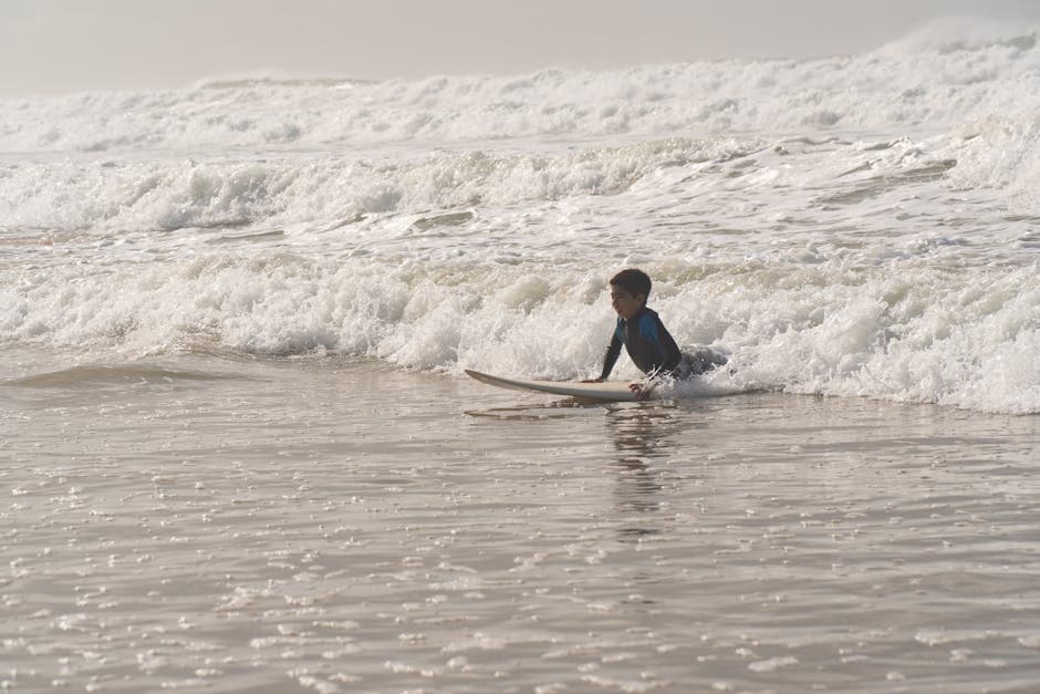 Young child learning to surf with an instructor at the beach, catching a wave in shallow water