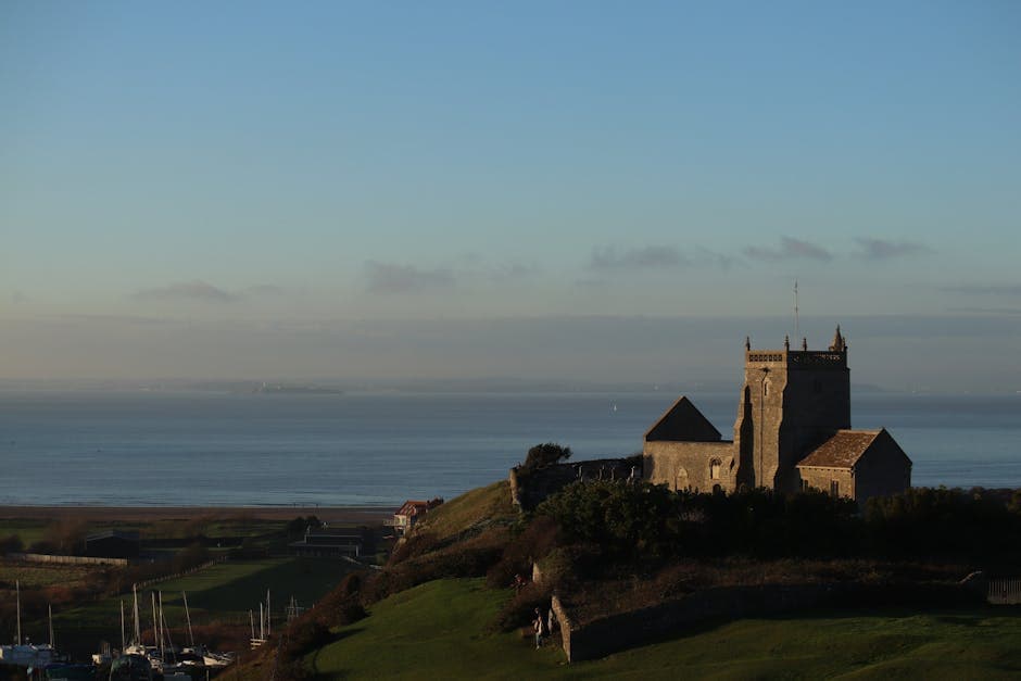A picturesque view of a historic church set against the backdrop of the sea during sunrise