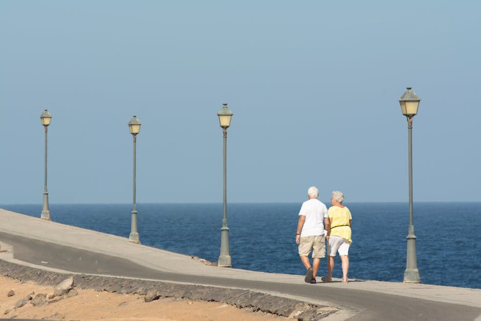 A couple walking side by side along a seafront promenade, relaxed and enjoying the coastal scenery