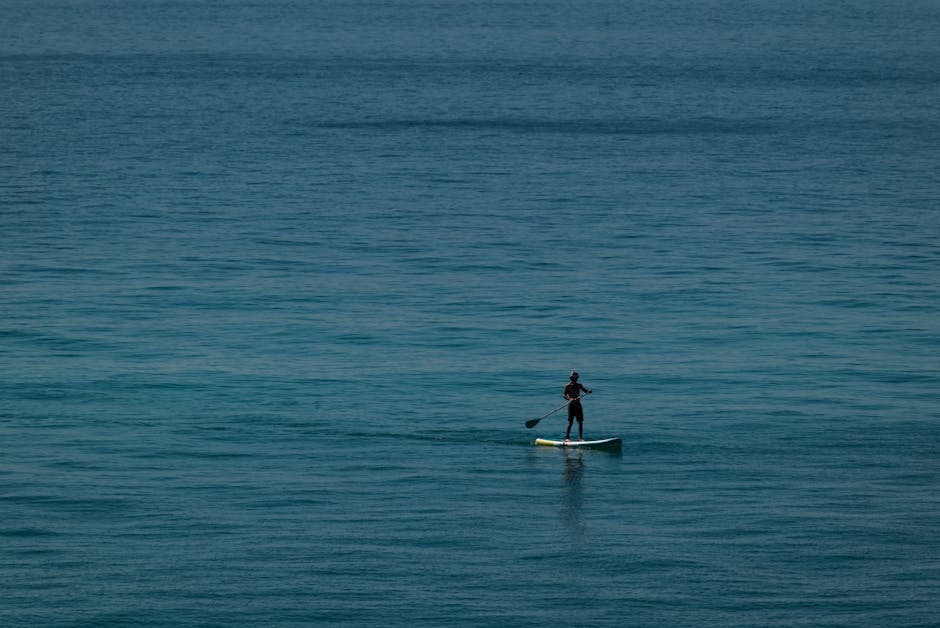 A lone paddleboarder enjoying a tranquil ride on the open ocean on a calm sunny day