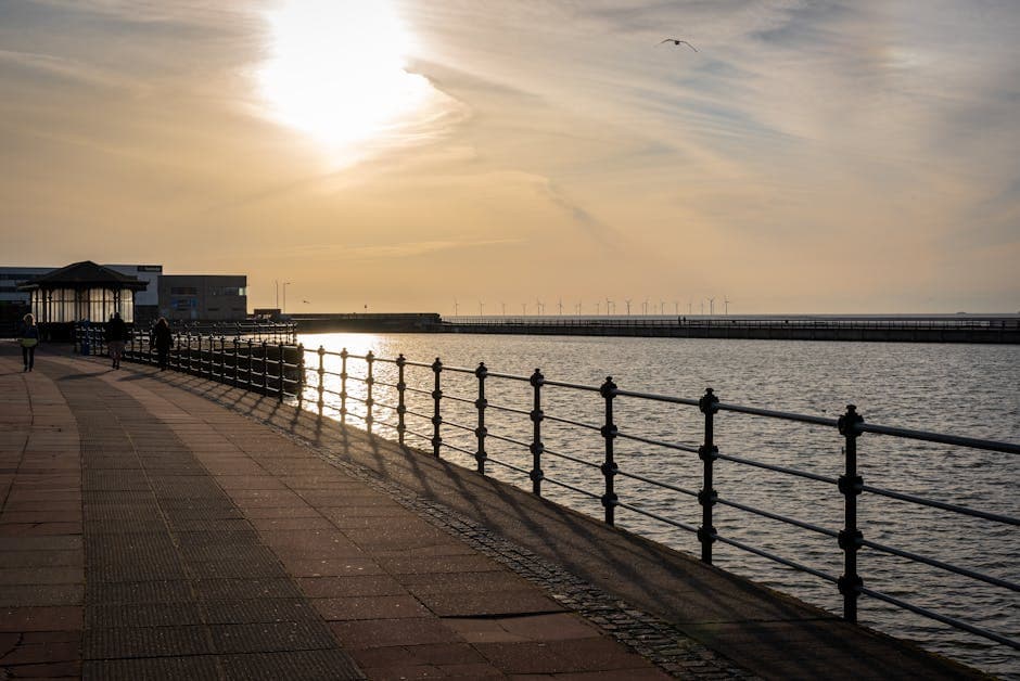 Beautiful sunset view over a coastal promenade with wind turbines visible on the horizon