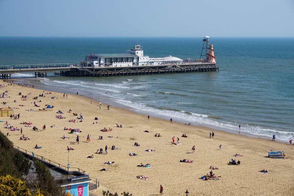 Bournemouth Beach on a busy summer day with the pier stretching into the sea and holidaymakers on the sand